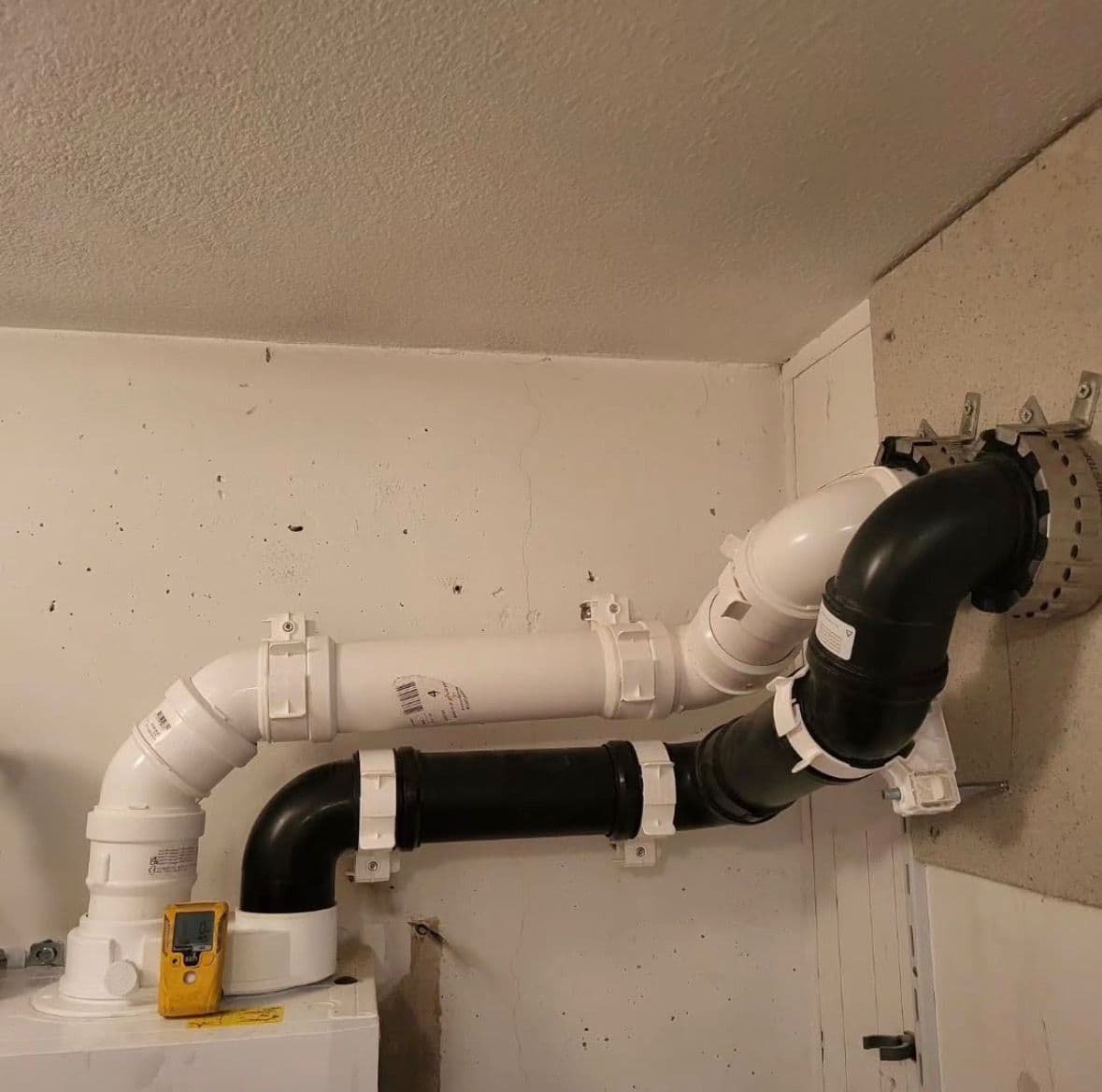 Nette rookgasafvoer installatie met witte en zwarte leidingen